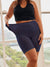 Front view of indigo 7-inch maternity slip shorts stretched to show elasticity and high-waist fit on model by a window